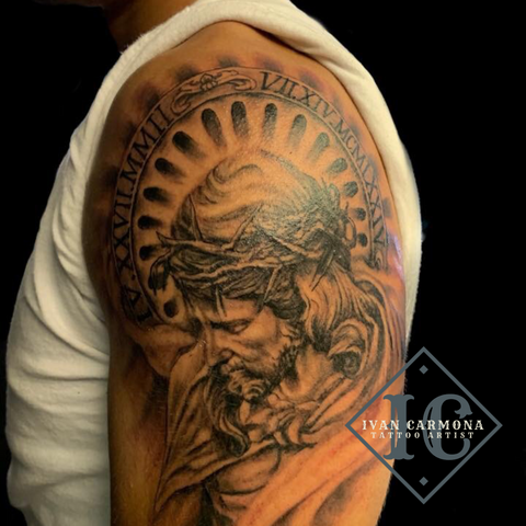 Religious Tattoo Of Jesus On The Upper Arm In Black And Gray With Roman Numerals Tatuaje Religioso De Jesus En El Brazo Con Numero Romanos Y Tinta Negra Y Gris